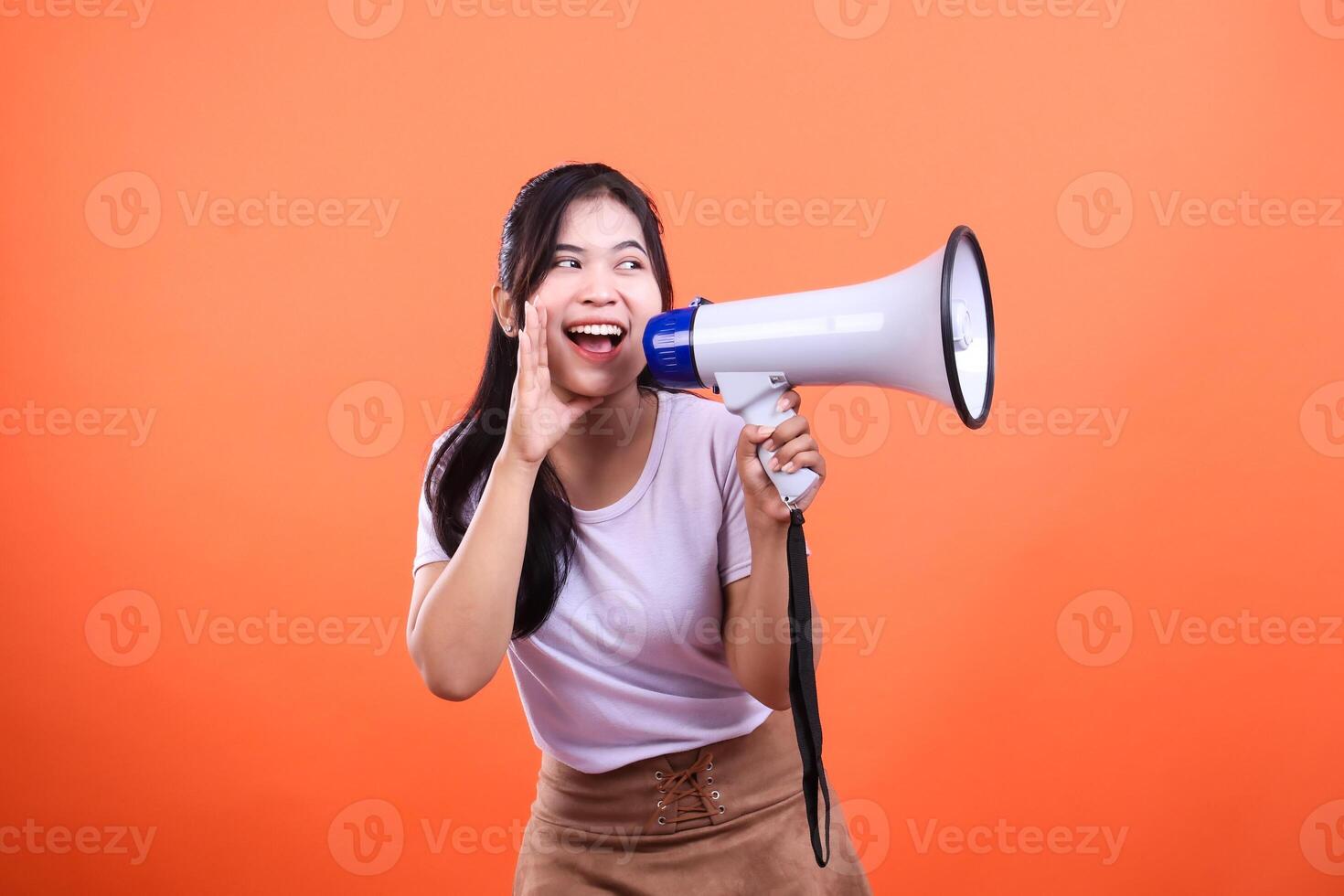 Woman with megaphone shouting isolated on an orange background, communication concept photo