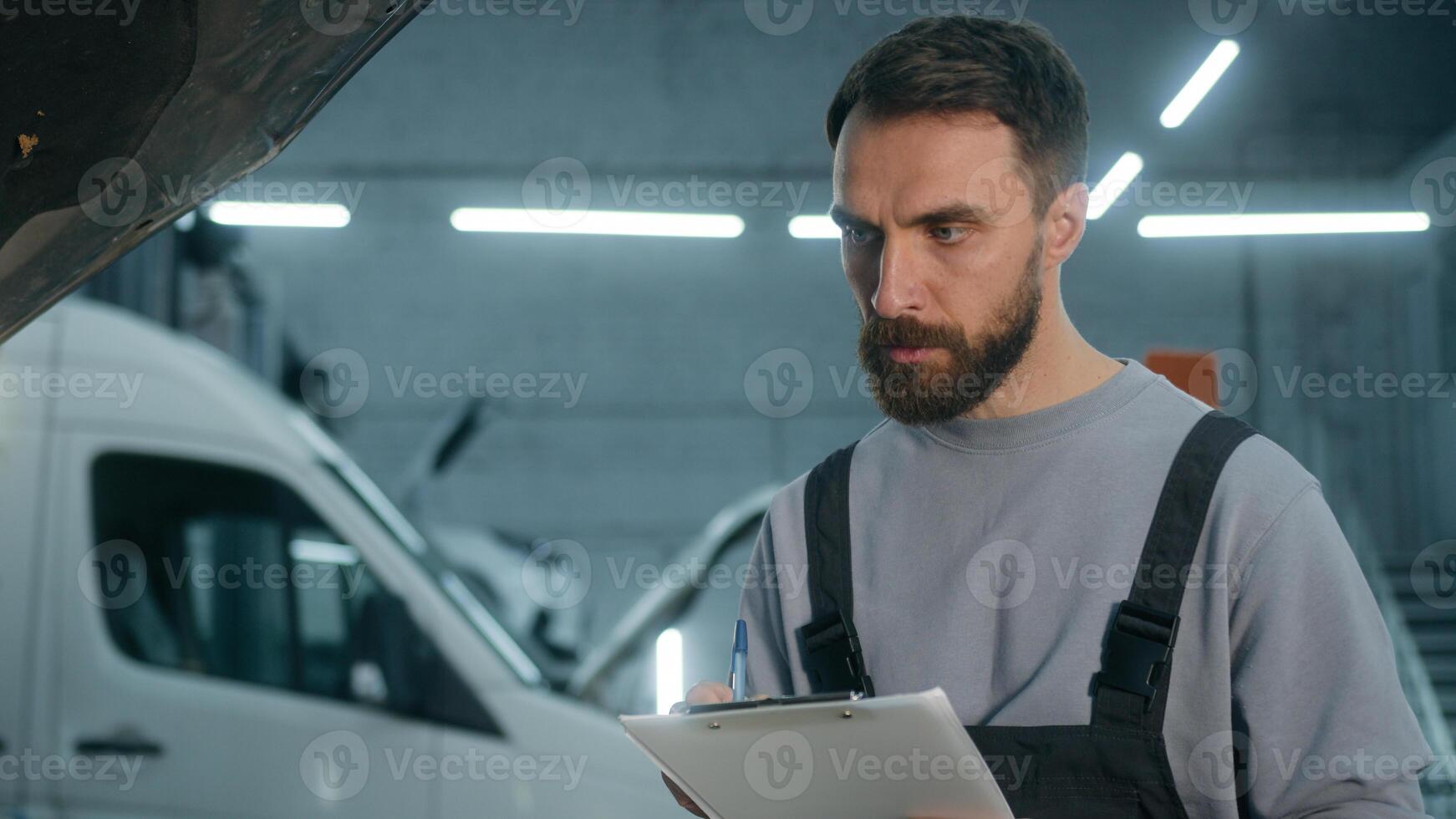 Auto mechanic professional technical expert Caucasian man male checking car manual maintenance write checklist on clipboard automobile diagnostics inspect transport at vehicle service station garage photo