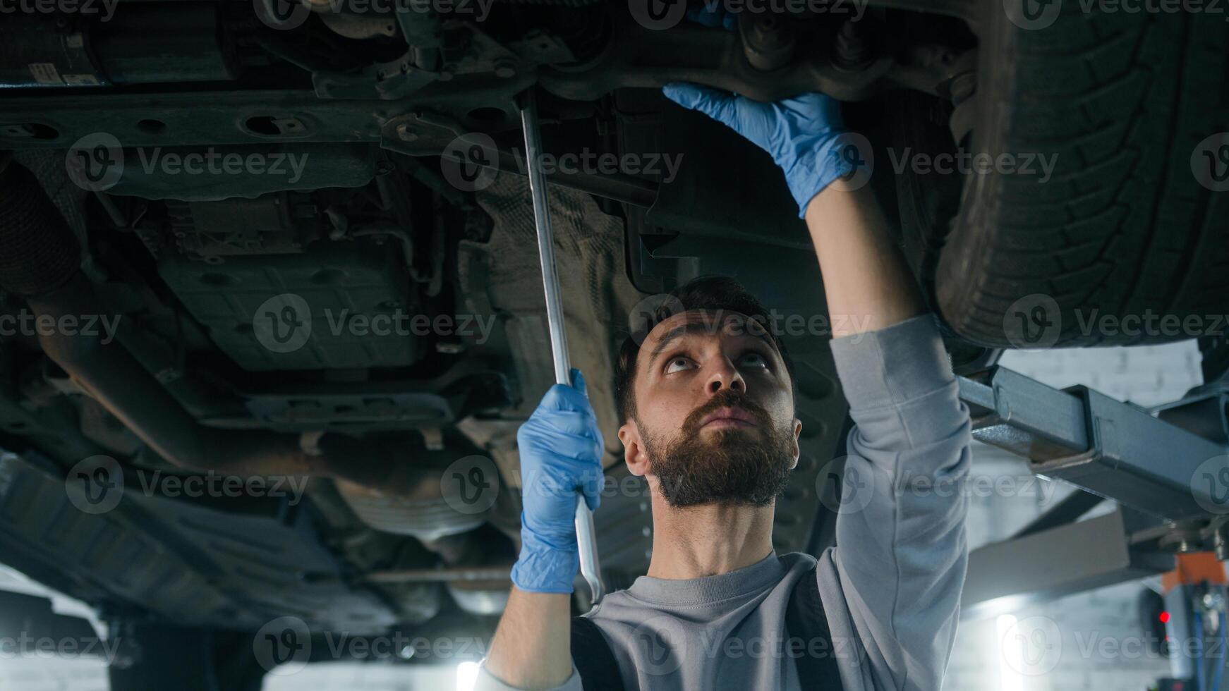 Caucasian man guy technician repairman auto mechanic repair truck in car service station male working underneath lifting vehicle in garage transport maintenance fixing automobile with mechanical tool photo