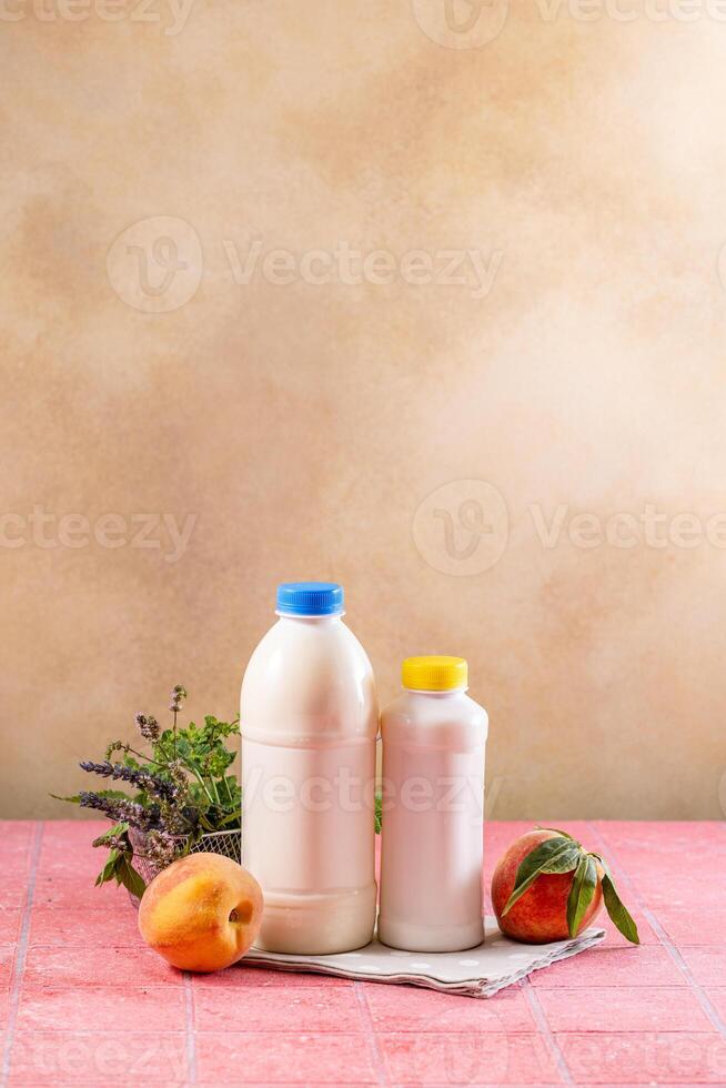 Peach flavored yogurt bottles standing on pink tablecloth photo