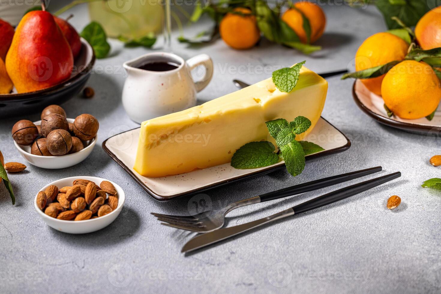 Gourmet cheese wedge with mint, fruits, and nuts on a table setting photo
