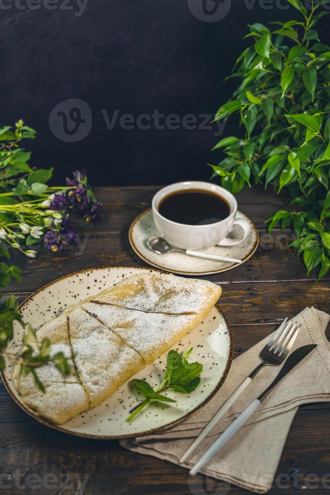 Delicious apple strudel with icing sugar served on a plate with coffee photo