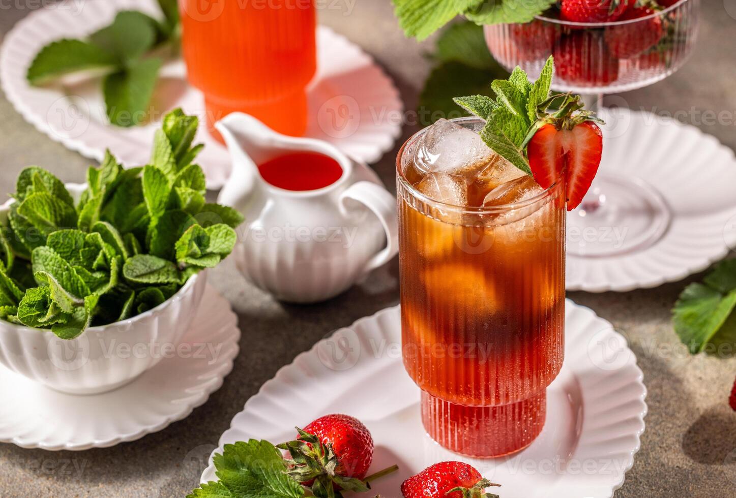 Refreshing glass of strawberry iced tea, adorned with vibrant fresh mint and juicy strawberries, resting elegantly on a white plate photo