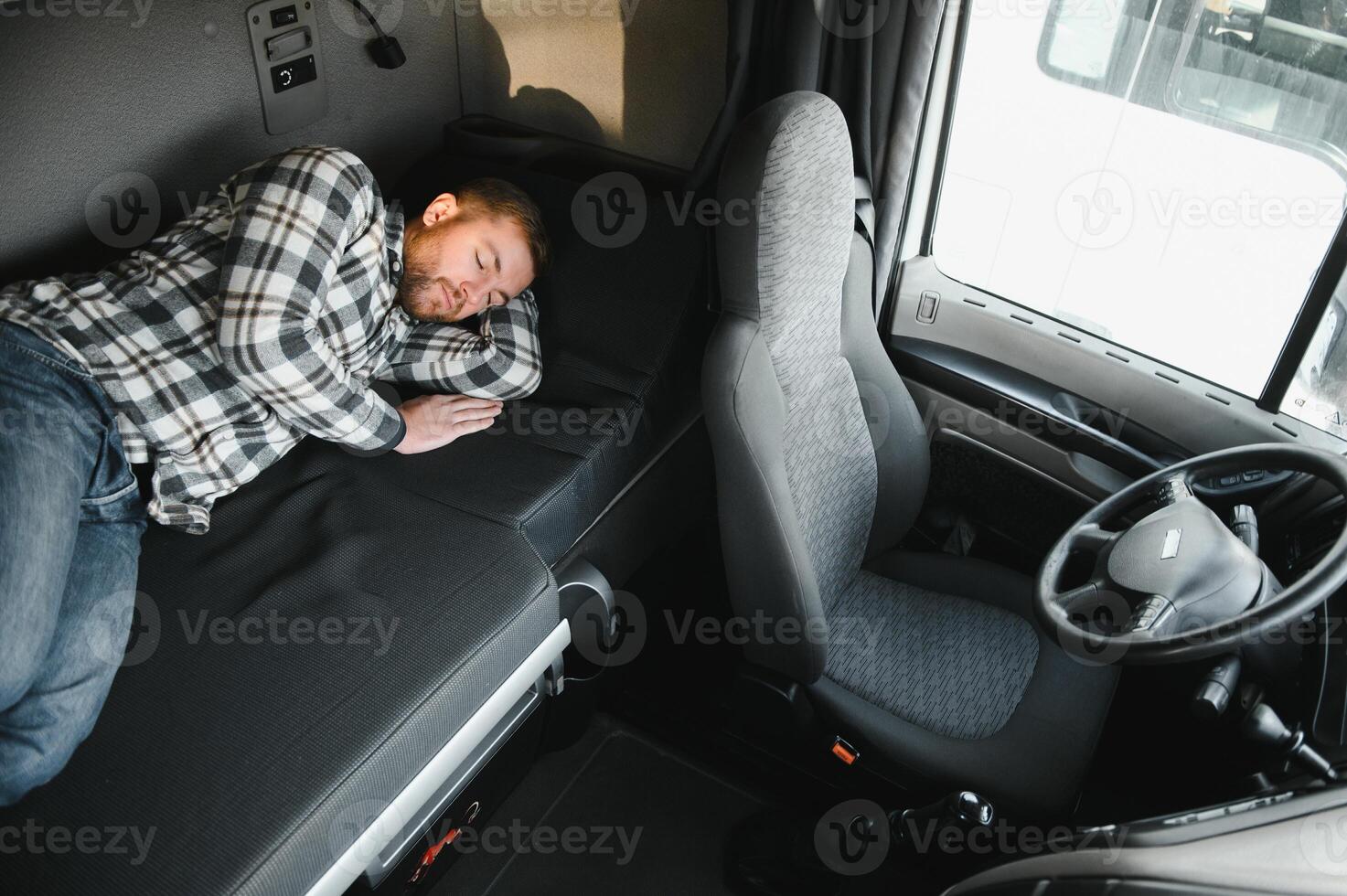 Truck driver sleeping in his cabin after working long routes overtime.Sleepy trucker taking a nap on a bed inside truck transporter. Lack of sleep photo