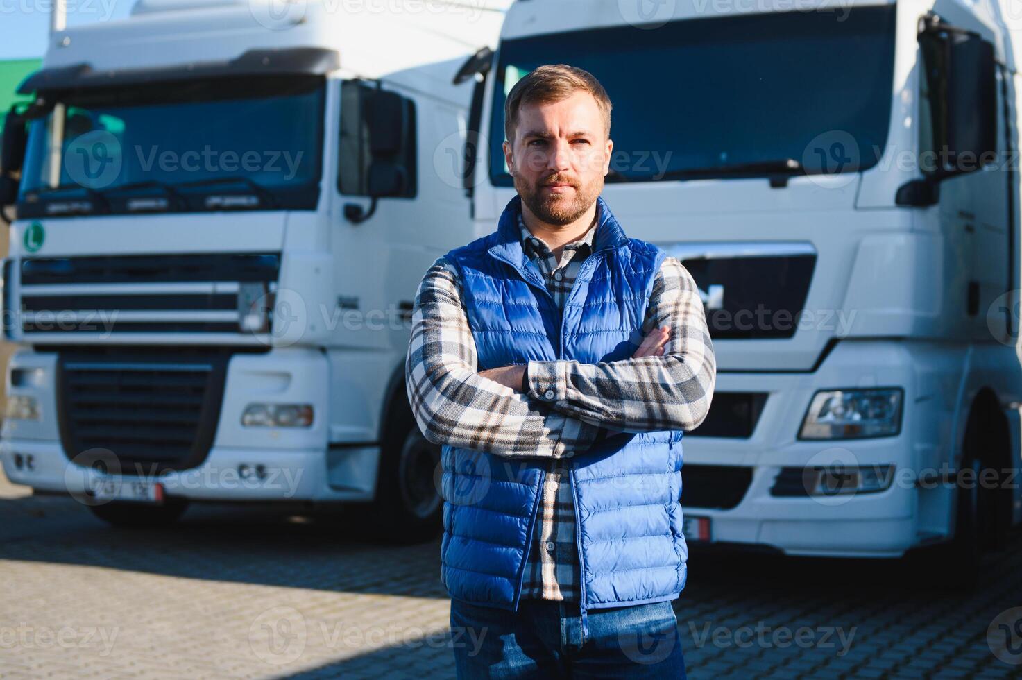 Happy truck driver standing with arms crossed in front of his truck photo
