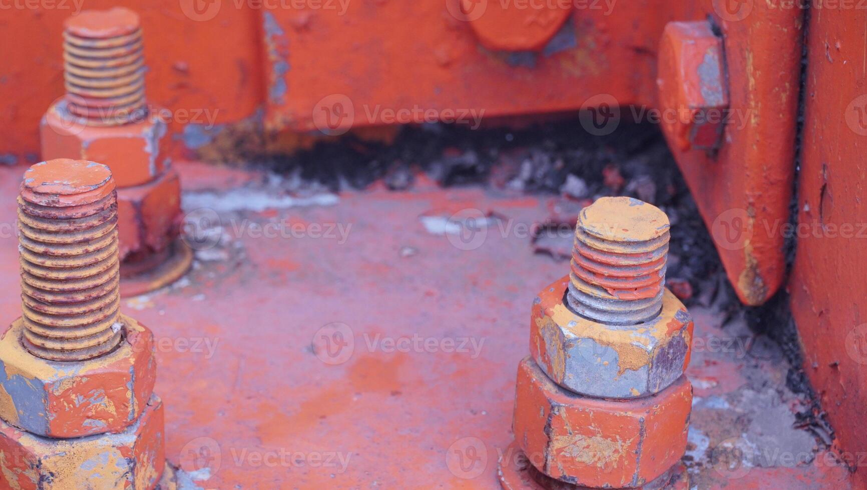 a close up of some bolts and nuts on an orange machine photo