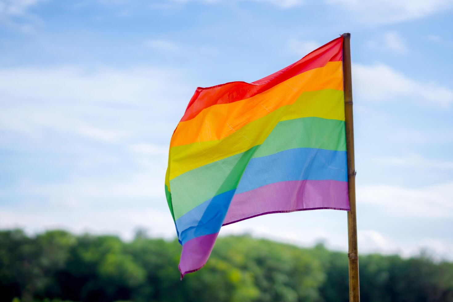 A rainbow flag is displayed against a clear blue sky. copy space An idea to call for everyone to support and respect gender diversity, human rights and to celebrate lgbtq in Pride Month. photo