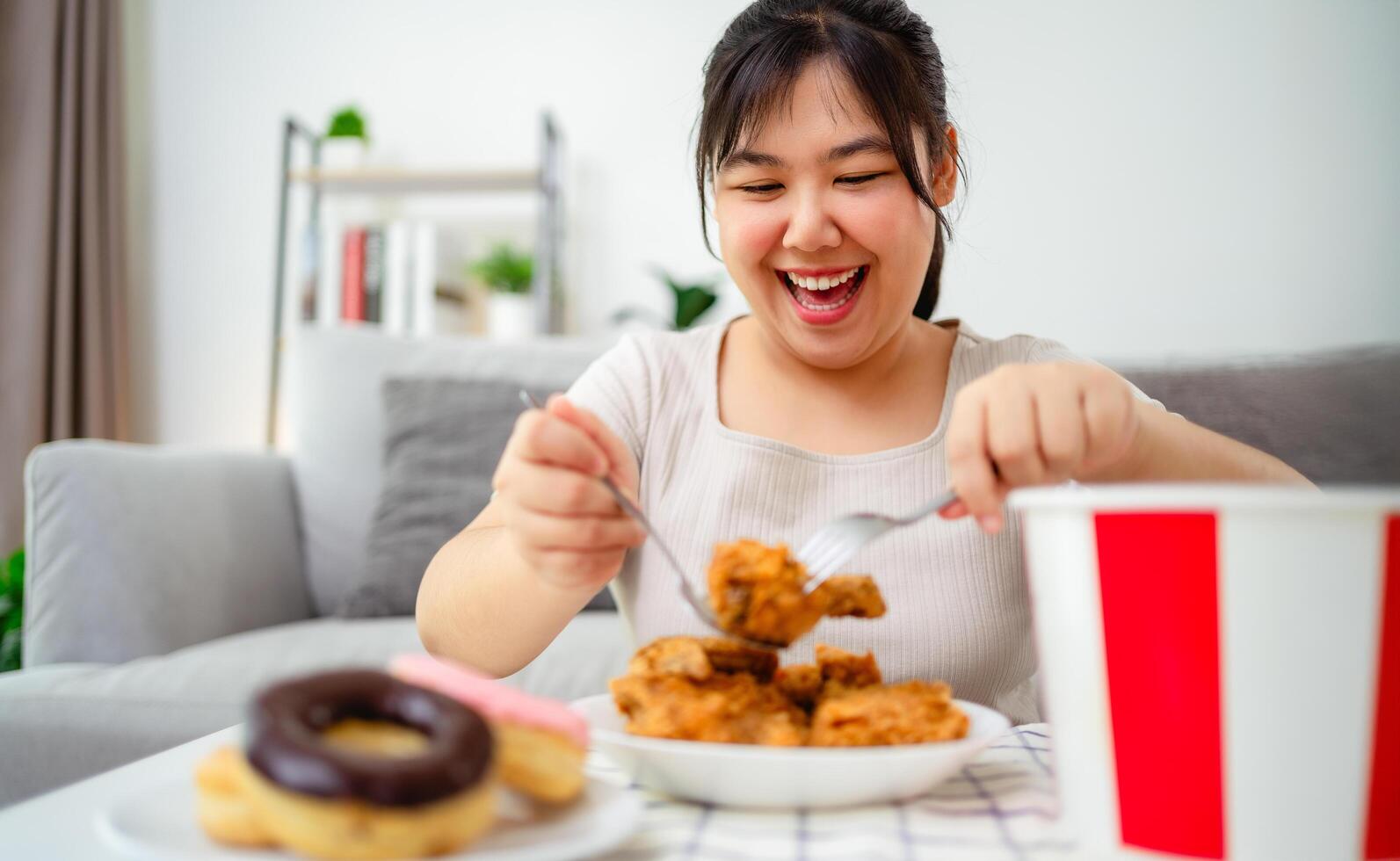 woman is happy eating fried chicken and donuts on a plate. Fast food, Unhealthy food concept. photo
