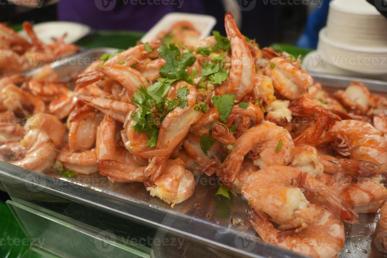 street food stall with vibrant array of deep fried prawn shrimps, golden brown savory treats are arranged on newspaper sheets, ready to be savored. photo
