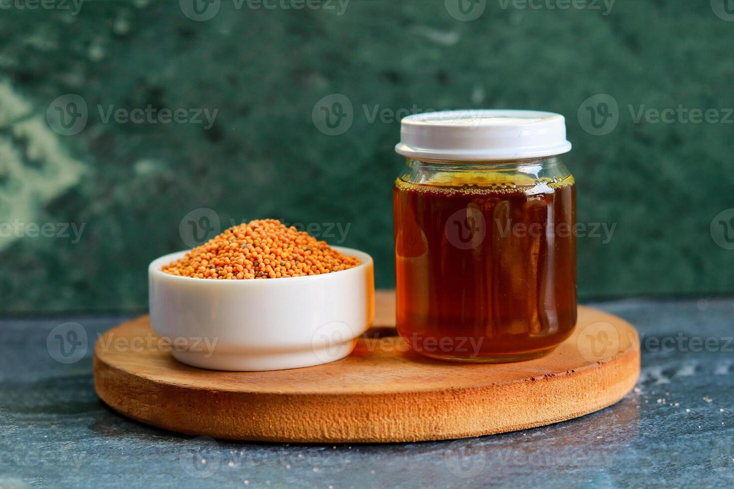 Bowl of Mustard seeds and a jar of Mustard oil on a table photo