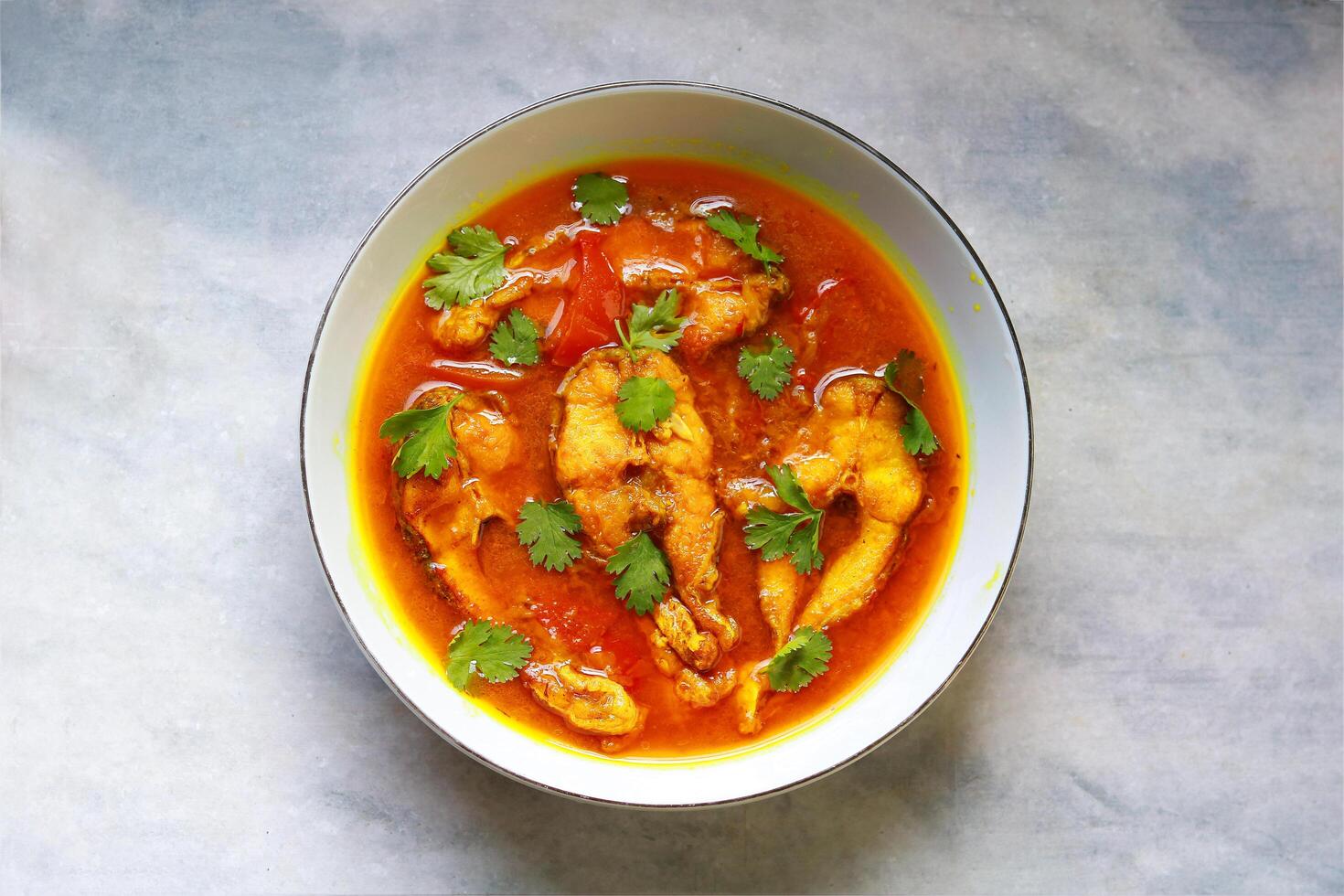 Fish curry in a bowl on a white table. Top view photo