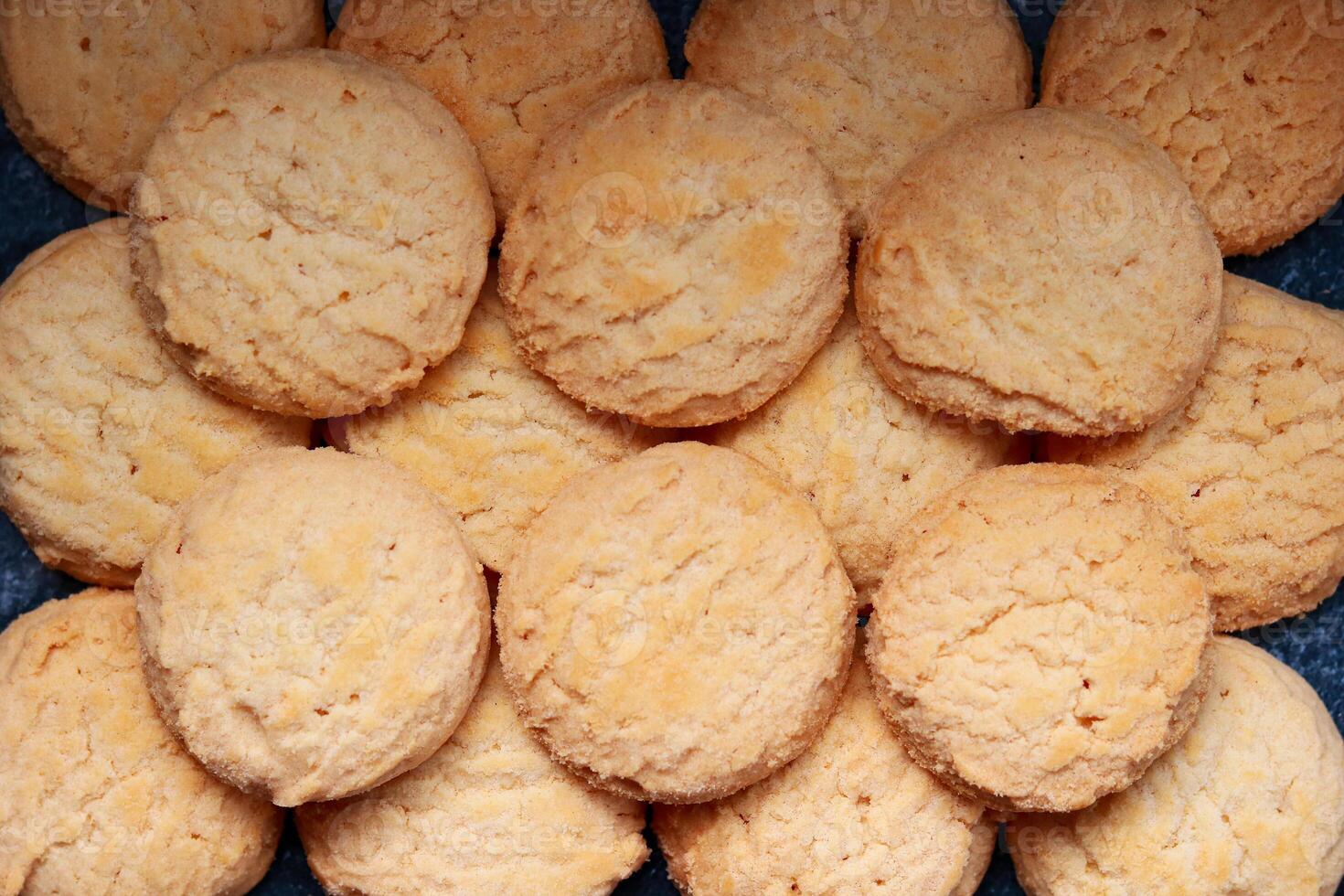 A pile of round cookies on a dark background. Top view. photo