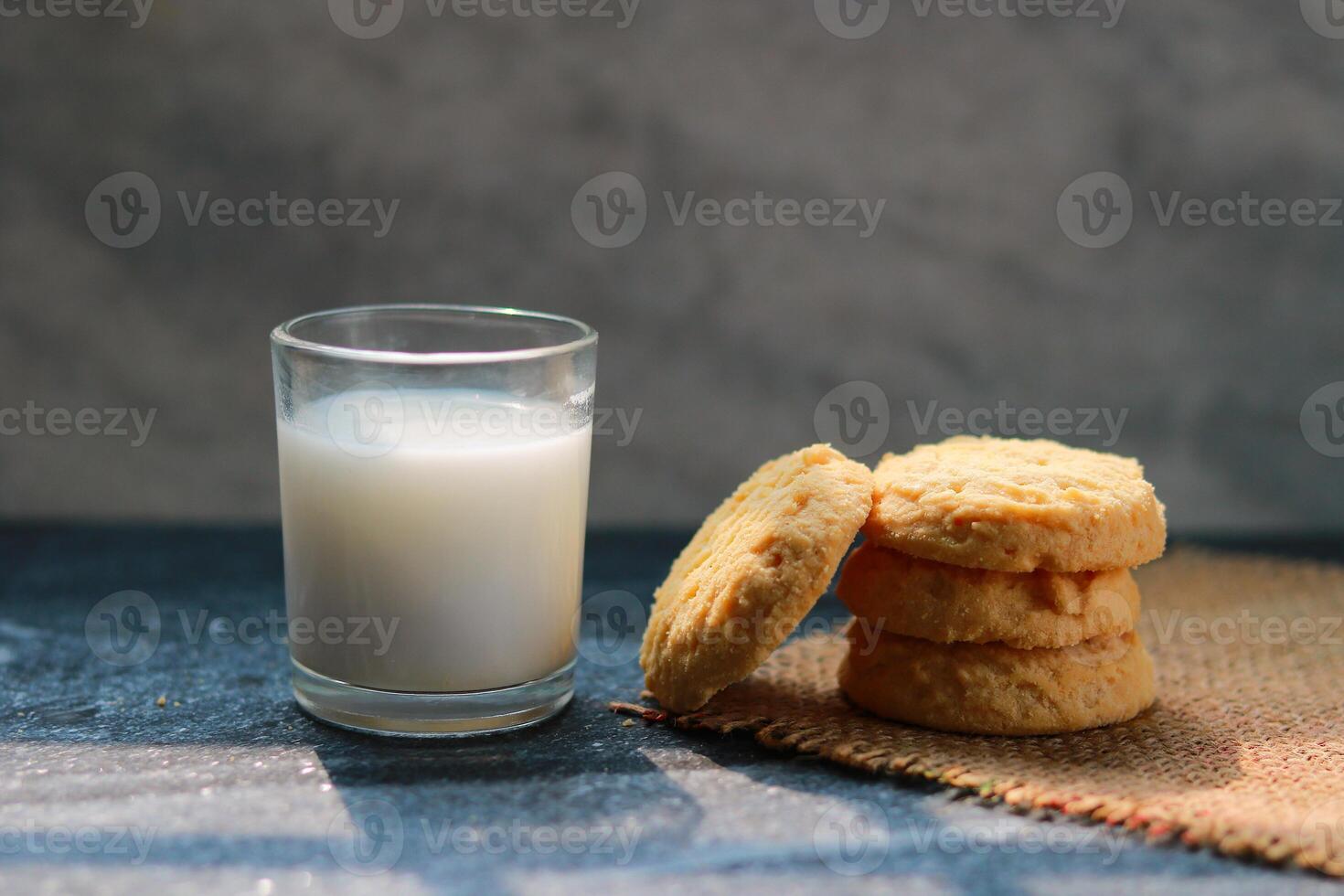 Milk in glass and some cookies on the table, closeup of photo