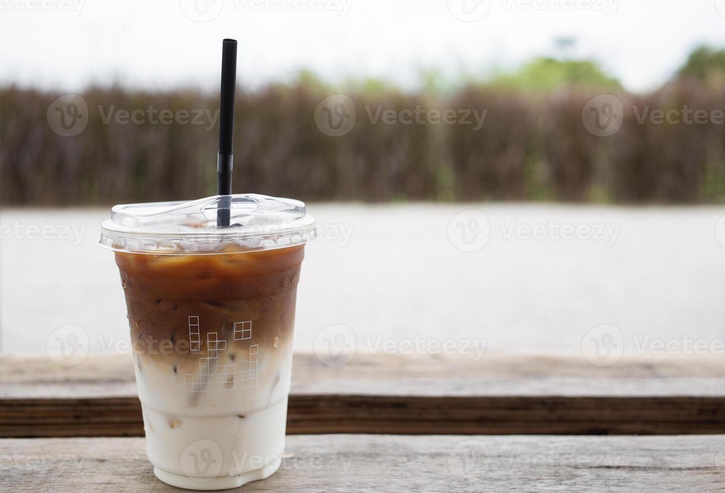 Iced of latte coffee cup on wooden backdrop grass nature background. Copy space for text photo