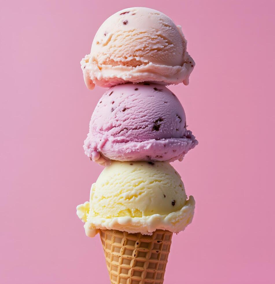 Delicious ice cream cone with three colorful scoops stacked high on a pink background photo