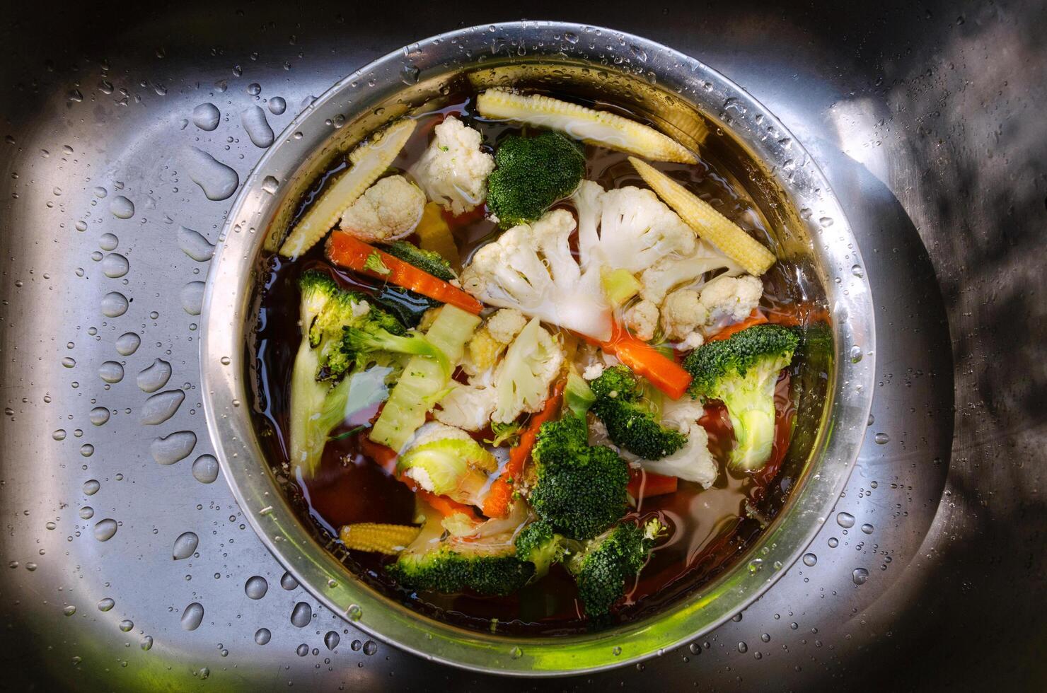 Vegetables at kitchen sink, washing fresh vegetables water with colorful fresh vegetables in the background, emphasizing healthy eating photo