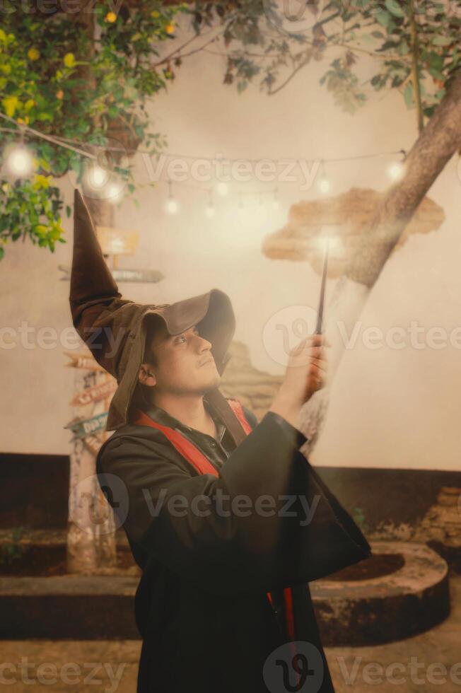 Man dressed in wizard attire performing magic in a whimsical garden at twilight photo
