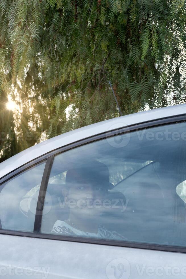 Person in a car looking out the window during a sunny afternoon photo