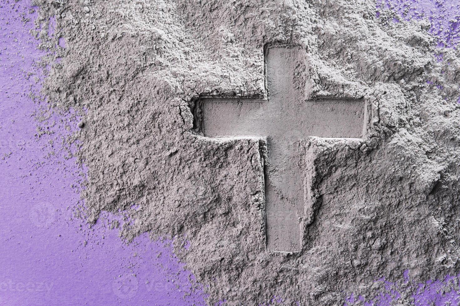 Cross imprint in gray ash on purple surface. Ash Wednesday symbolism and texture contrast photo
