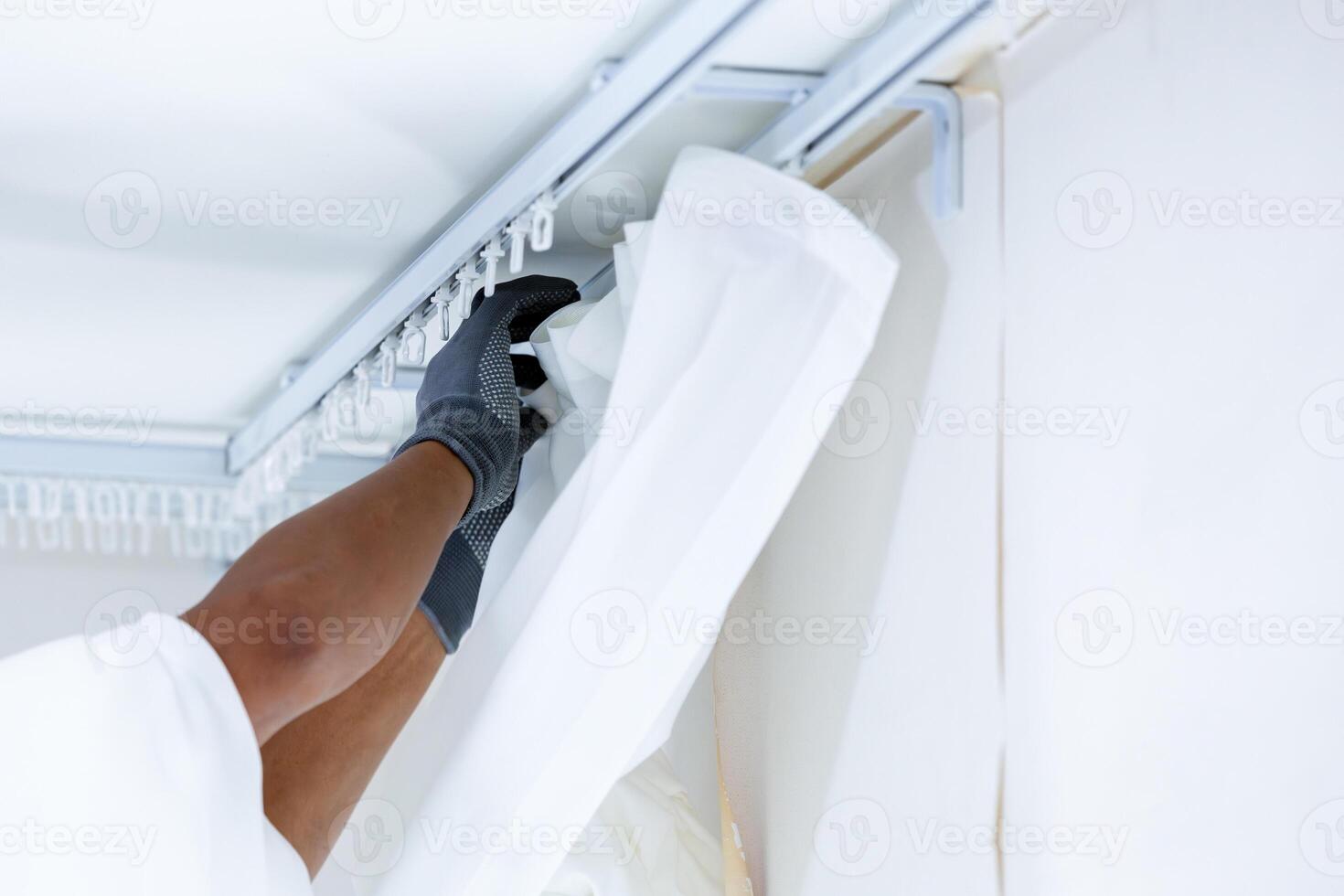 Worker man hand hanging window curtain, Repairman installs a curtain rod and hangs curtains in the house photo