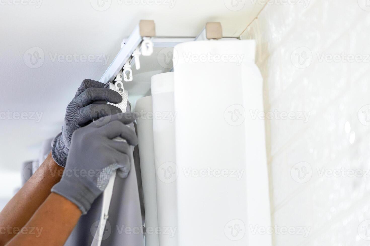 Repairman installs a curtain rod and hangs curtains in the house, Worker hanging window curtain photo
