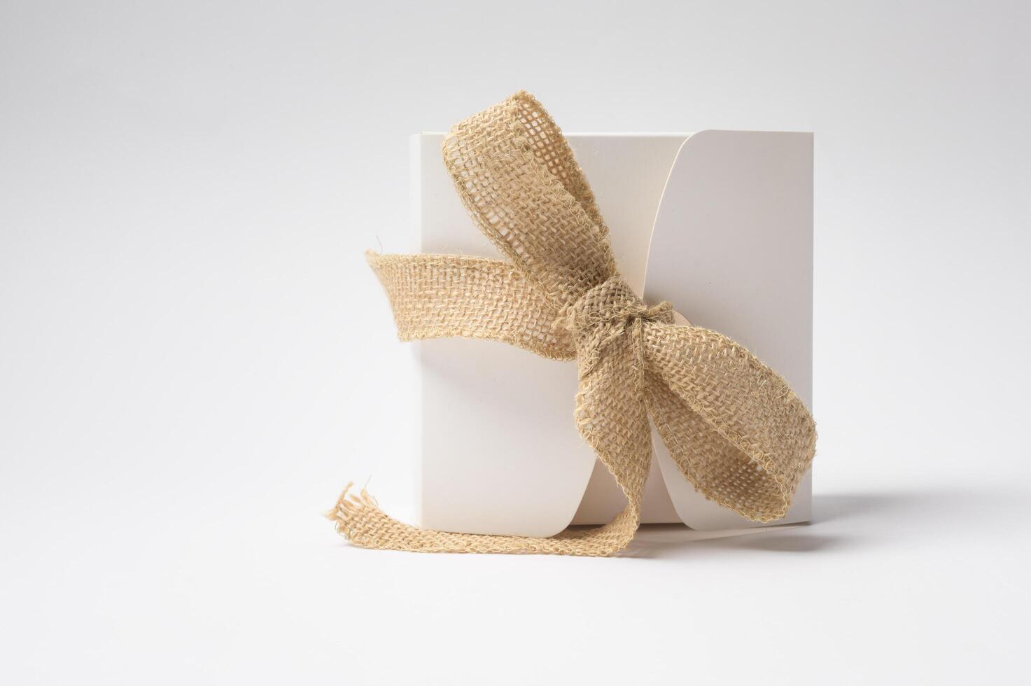 Elegant White Gift Box Wrapped in Burlap Ribbon on a Clean White Surface photo