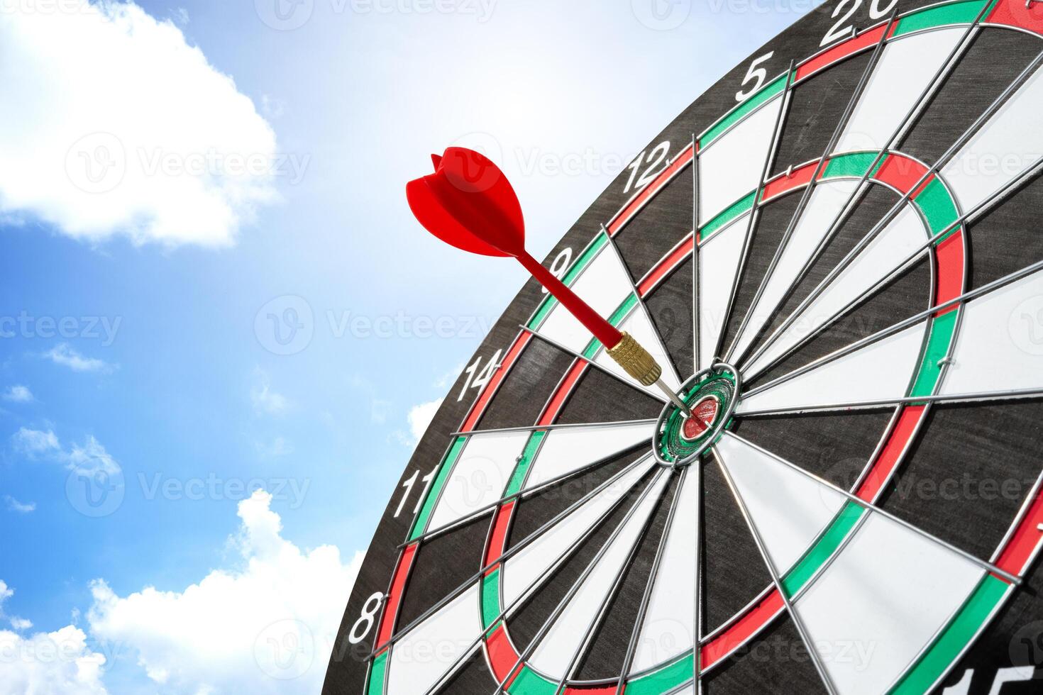 Darts with target board on blue sky background photo