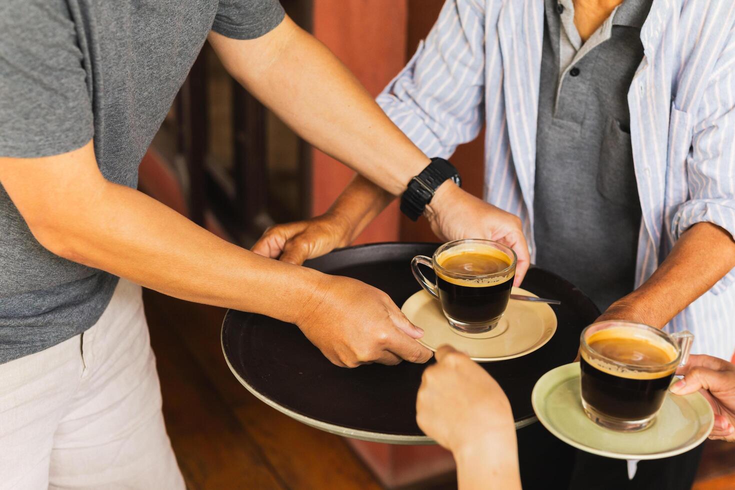 Senior man serving coffee with help of customer at cafe. photo