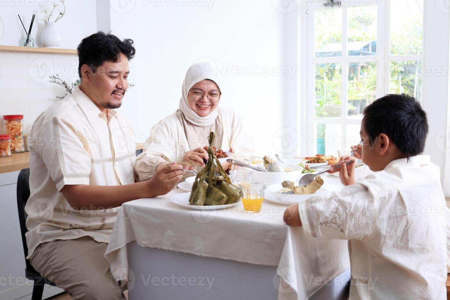 Young Asian Muslim Family , Father, Mother, and Two Kids Eat Ketupat Lebaran Together, photo