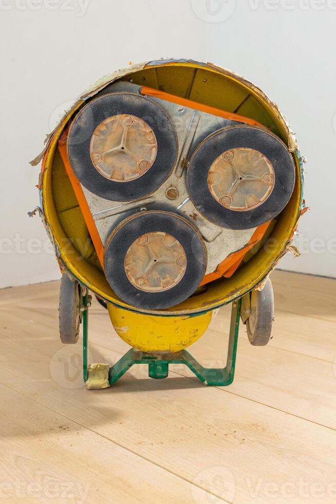 A yellow and green floor polishing machine on a light wooden floor, showing three circular polishing pads in a triangular arrangement. photo