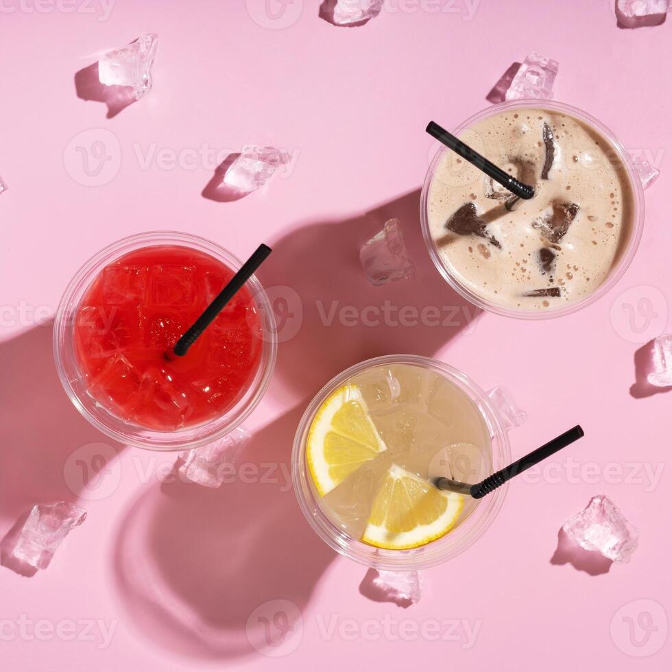 Three takeaway glasses of summer drinks with ice. Lemonade on colored background photo
