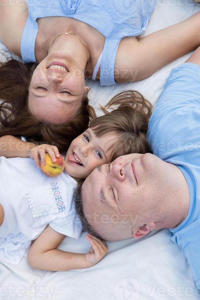 Mom, dad and daughter having fun on a picnic. Family portrait photo