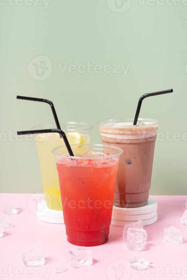 Three takeaway cups of summer drinks with ice. Lemonade on colored background photo