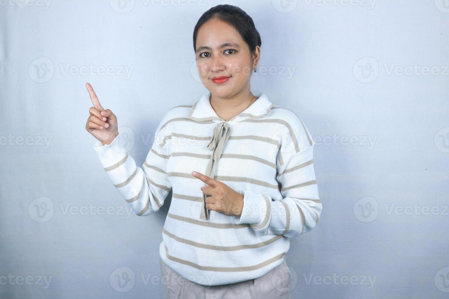 Beautiful asian woman pointing her finger to empty copy space isolated on white background photo