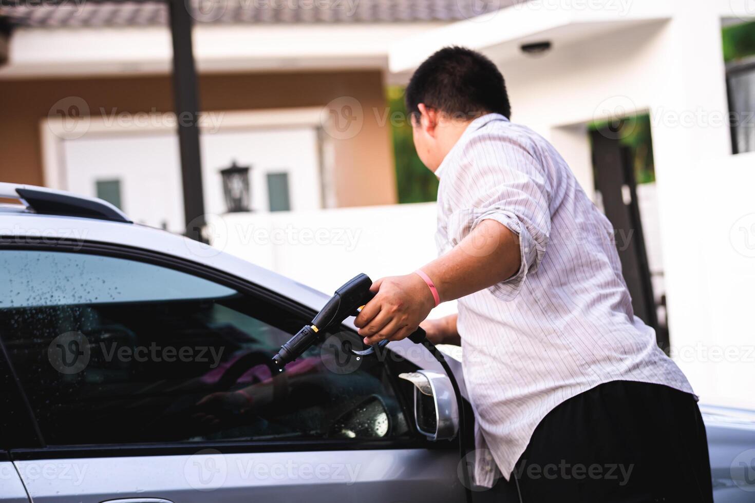 Side view of the man is holding a high pressure cleaner to clean the car to welcome good luck on Chinese New Year or New Year's Day. photo