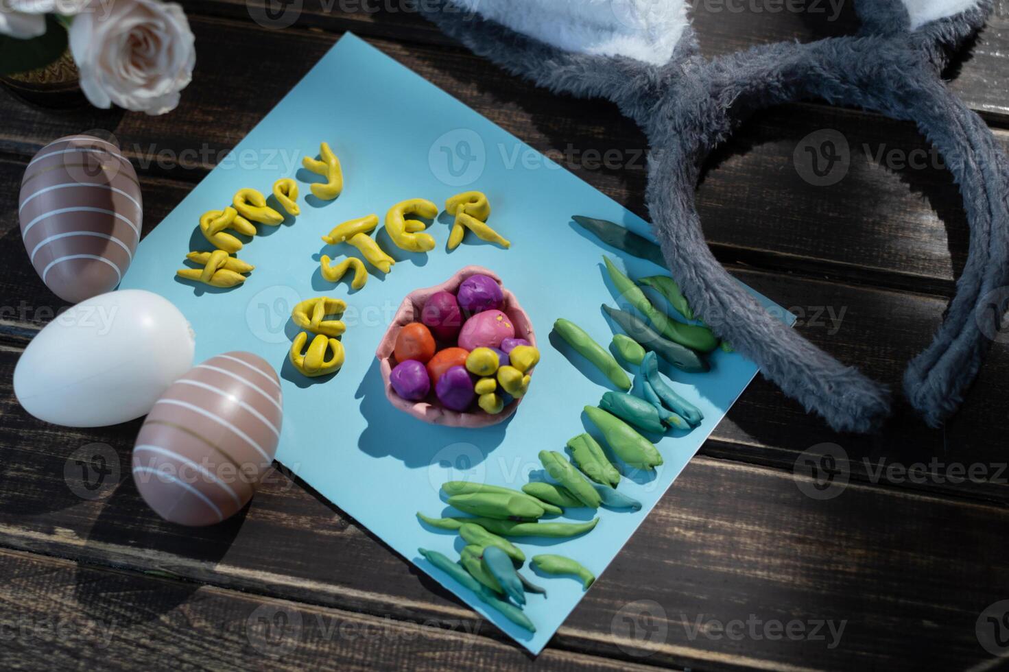 DIY Easter childish greeting card, coloured easter eggs and bunny ears on wooden table. Happy Easter congratulation photo
