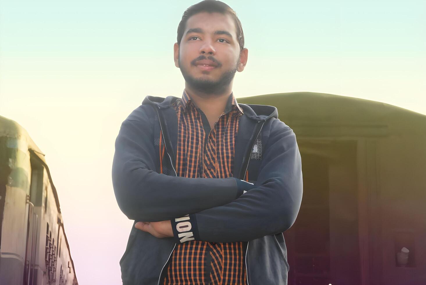 Portrait of a young Asian man standing with arms crossed confidently, set against the backdrop of a train photo