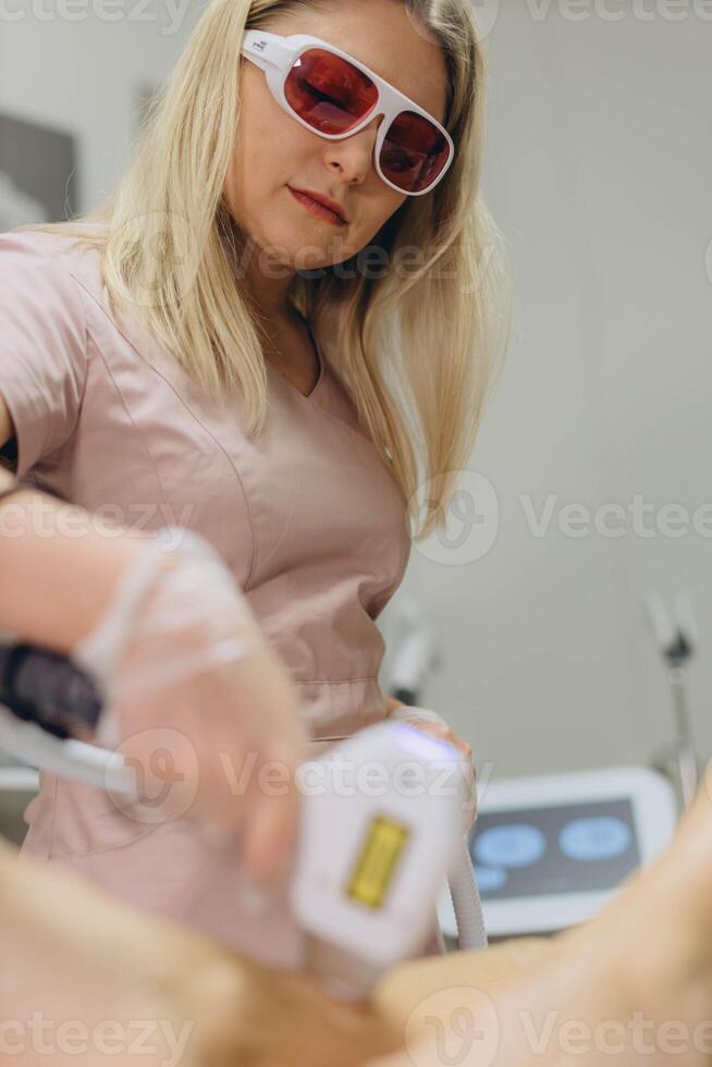 Client undergoing body hair removal with laser treatment at a beauty clinic photo