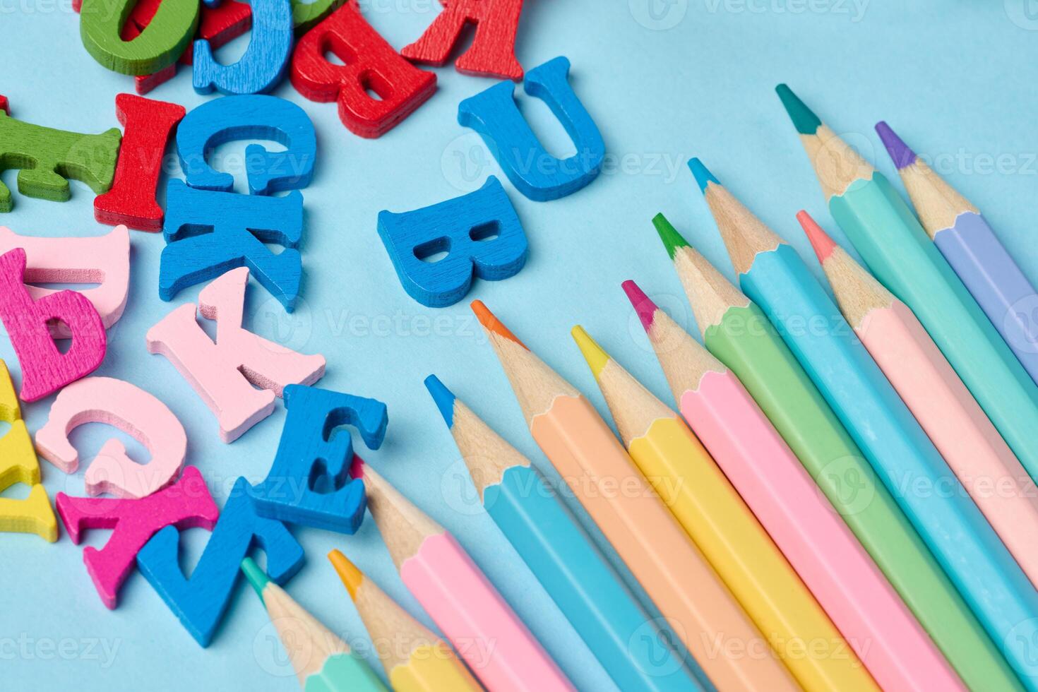 Multicolored wooden pencils and letters on a blue background photo