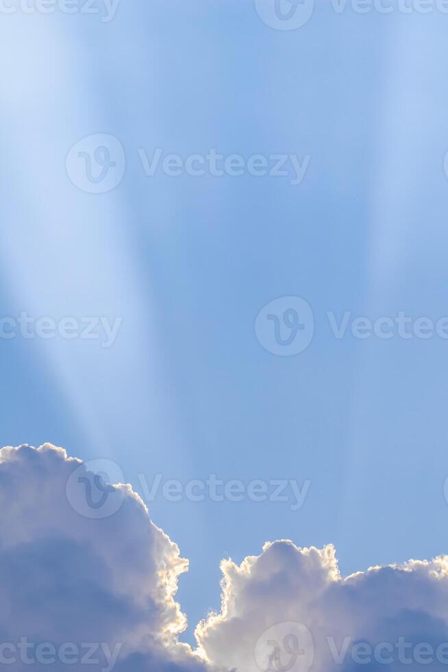 Background from blue sky with sun rays across clouds photo