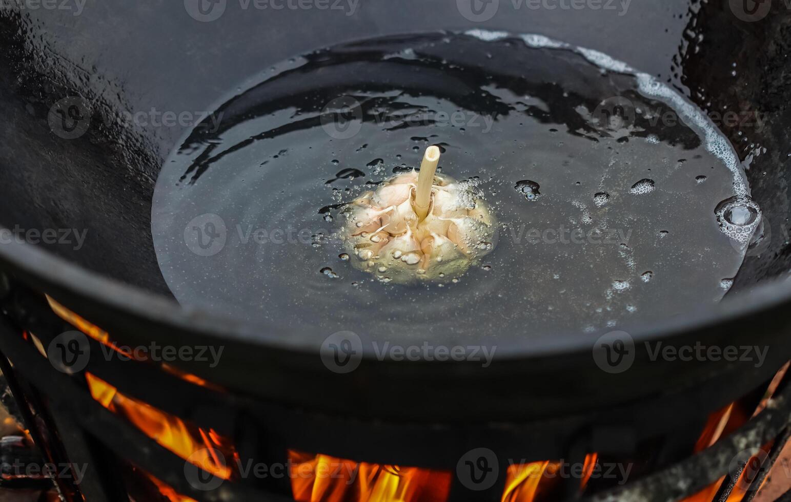Cooking rice pilaf in a large cast-iron pot on fire photo