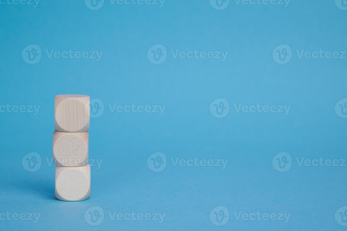 three stacked wooden blocks against blue background with copyspace photo