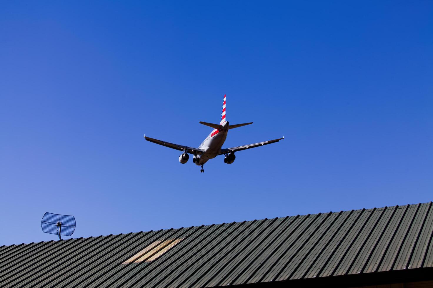 San Luis Obispo, CA, 2024 - Low Flying Jet Airplane In Blue Sky Over Roof photo
