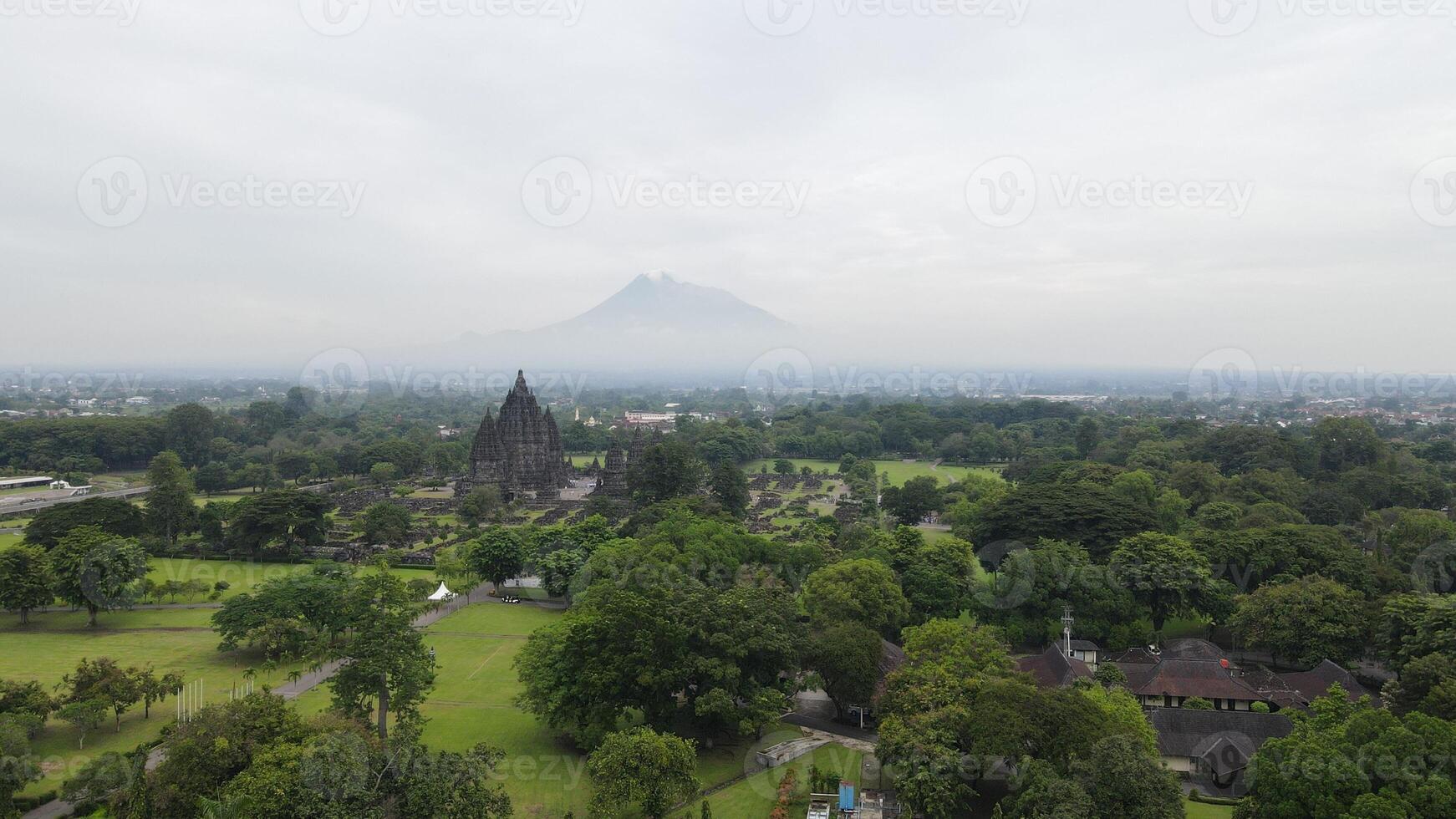 aerial view of the Prambanan temple area in Yogyakarta, with the majestic Mount Merapi clearly visible in the background. photo