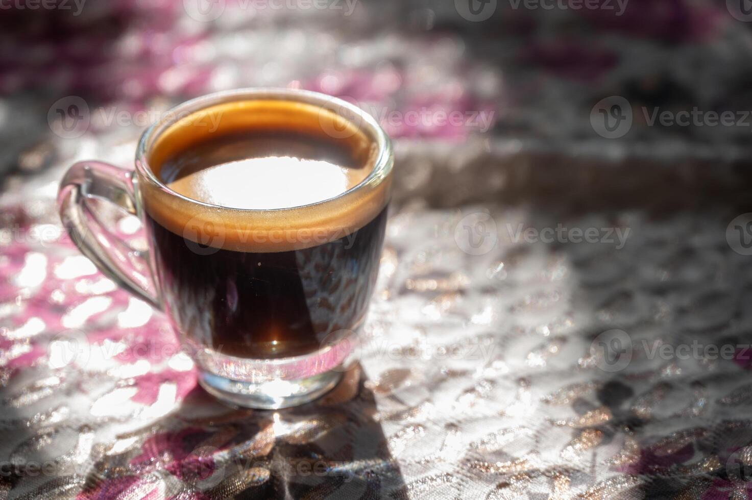 A shot glass of black coffee on table. Black coffee is rich in antioxidants, which can fight cell damage and reduce your risk of serious health conditions. photo