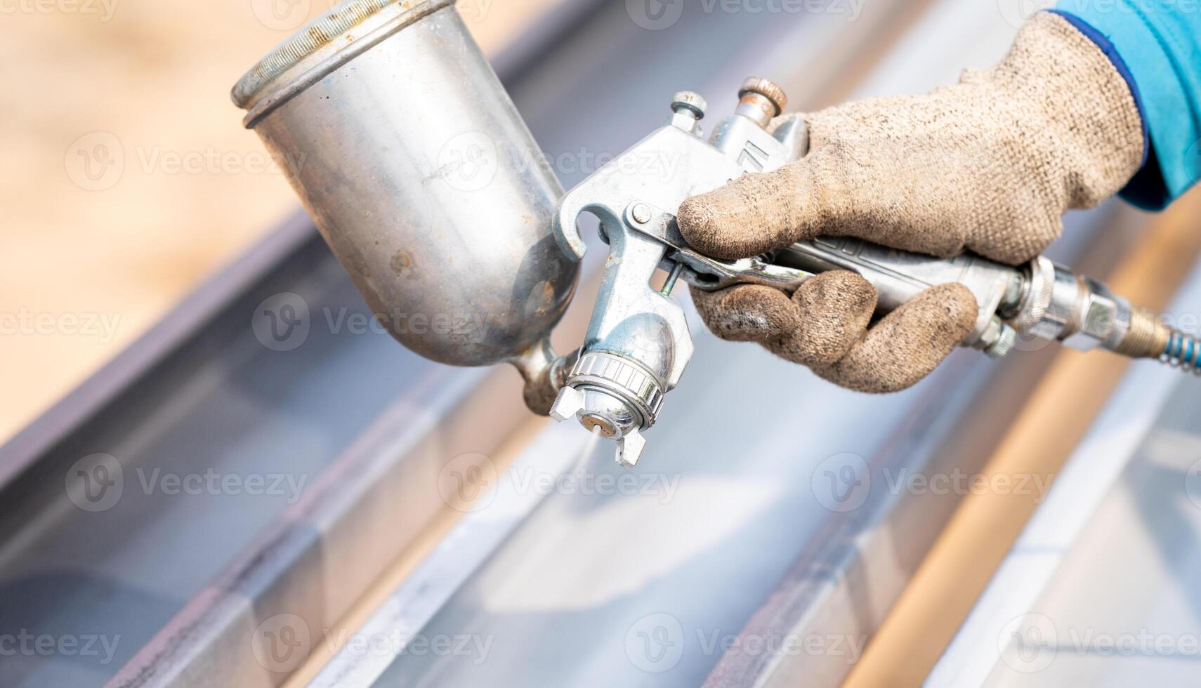 Construction worker painting metal structure surface coating with a spray gun at construction site. Metal corrosion and rust protection. Industrial precision. Protective coating to metal photo