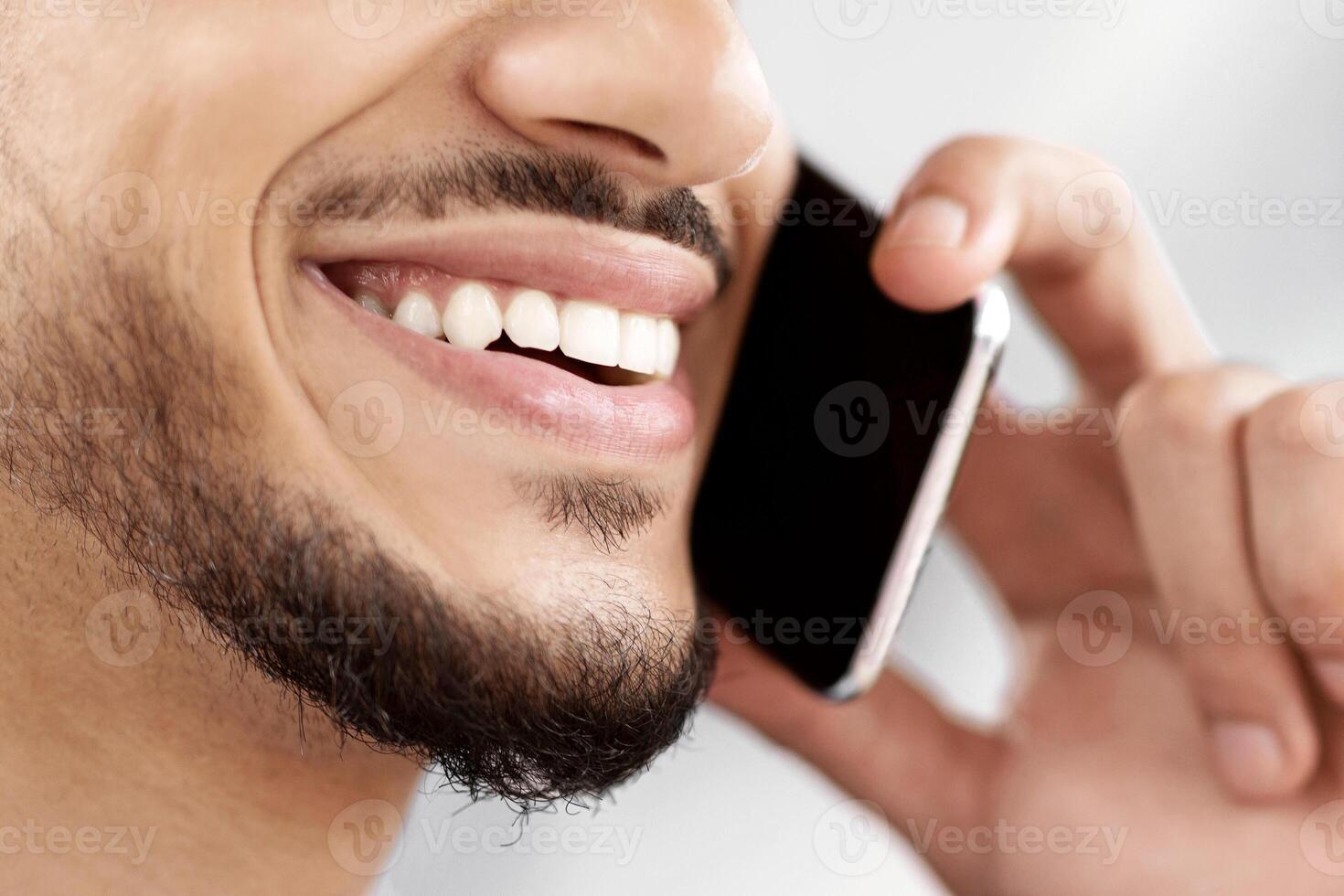 Phone Call. Closeup Shot Of Smiling Arab Man Talking On Cellphone, Unrecognizable Middle Eastern Guy Enjoying Mobile Communication, Having Pleasant Conversation, Selective Focus, Copy Space photo