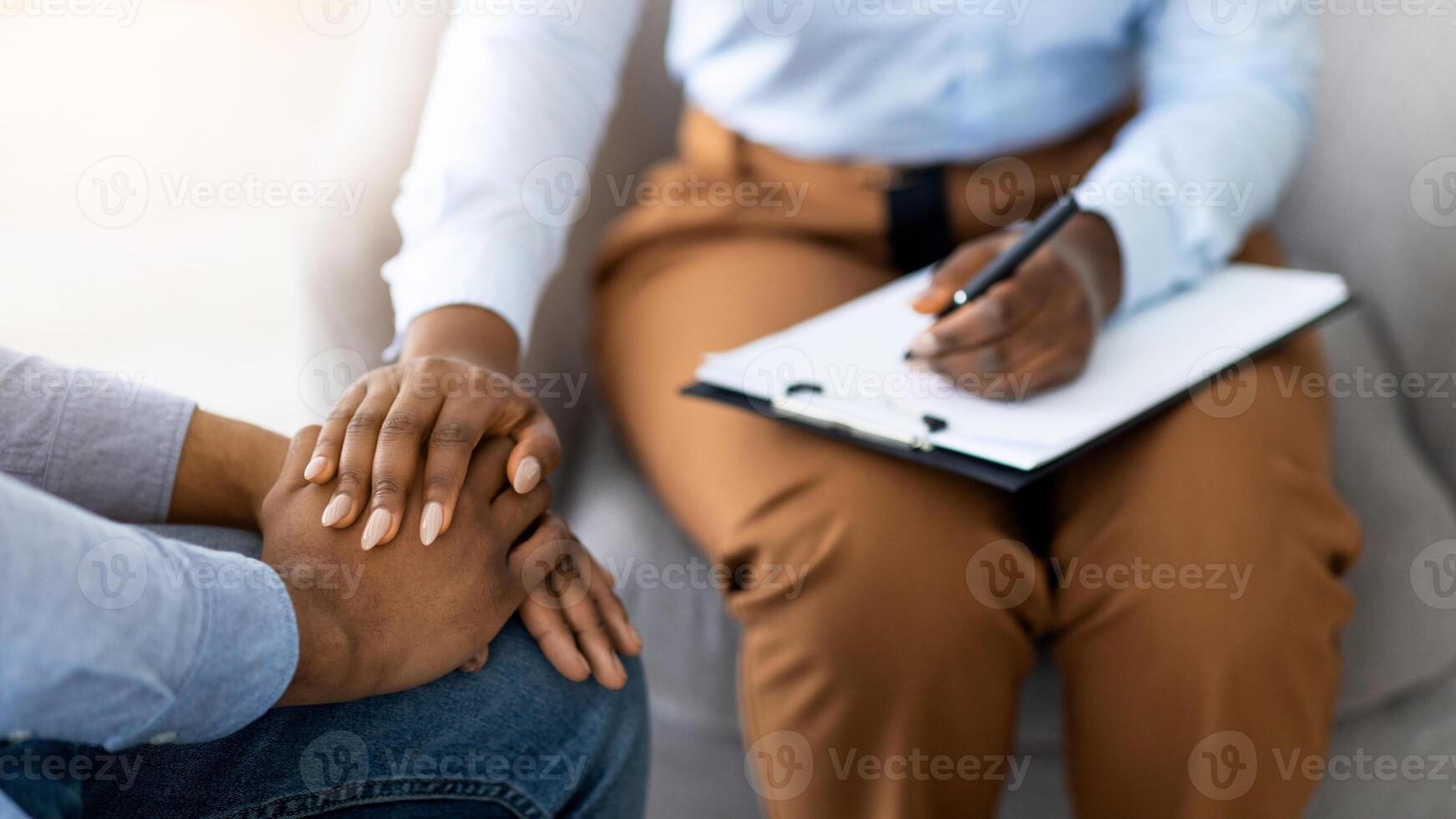 Unrecognizable psychotherapist supporting depressed male patient, touching his hands at medical office, closeup. Counselor comforting young guy with mood disorder, cropped view photo