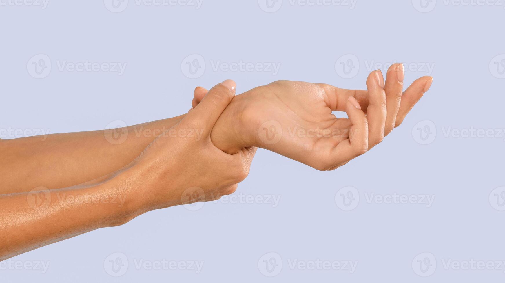 Closeup of female arms holding painful wrist caused by prolonged work on the computer laptop. Carpal tunnel syndrome, arthritis, neurological disease concept. Numbness of the hand, blue studio wall photo