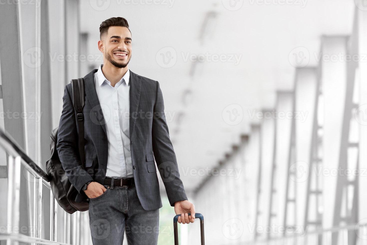 Ready For Trip. Handsome Arab Guy Walking With Suitcase At Airport Terminal, Smiling Young Middle Eastern Man Carrying Luggage While Going To Flight Boarding Gate, Enjoying Upcoming Air Travel photo